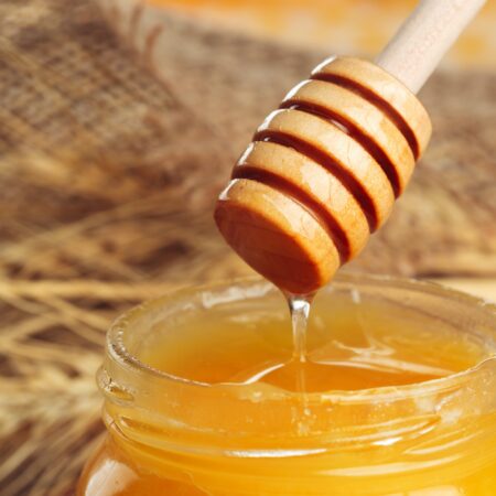 Honey background. Sweet honey in glass jar on wooden background